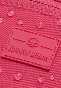 Tessuto rosa testurizzato con gocce decorative trasparenti e un patch logo in rilievo etichettato "JOHNNY URBAN". Il design presenta una finitura liscia.