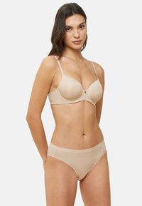 Conjunto de sujetador color beige y bragas a juego, textura suave, brillo sutil, soporte con varilla, tirantes ajustables, diseño sin costuras, detalle de hardware mínimo.