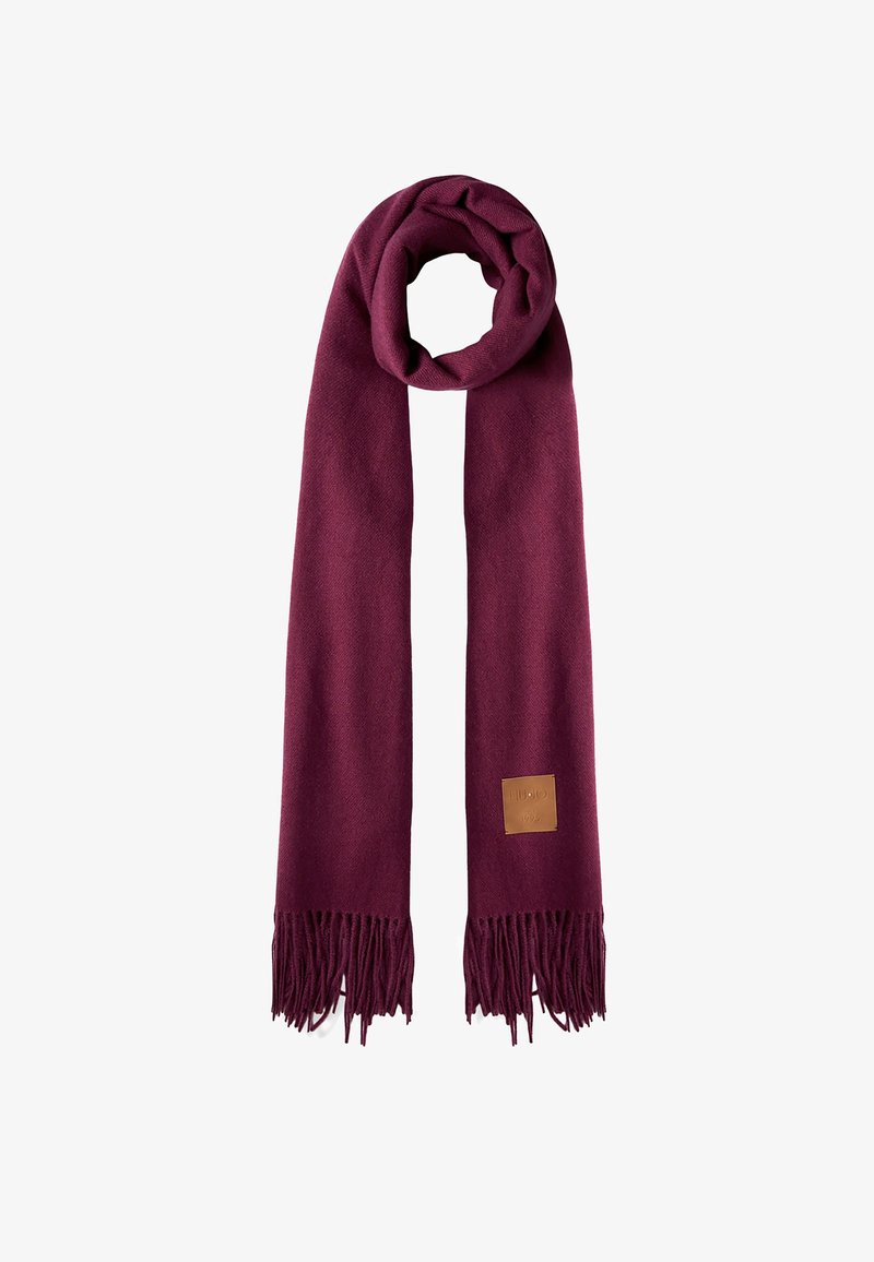 Écharpe douce et longue couleur bordeaux avec des bouts à franges et une petite pièce en cuir beige d'un côté, pliée en boucle en haut.