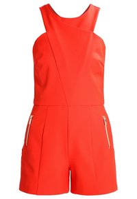 Röd ärmlös jumpsuit med hög halsringning, diagonala sömdetaljer och två fickor med dragkedja på sidan. Tillverkad av mjukt, stretchy tyg.