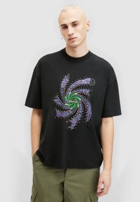 Svart bomullströja med ett spiraltryck i lila och grön, med prickiga detaljer och texten "Allsaints" i mitten.