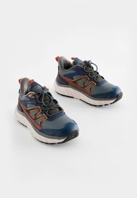 Baskets de sport pour hommes en bleu marine et gris, avec un accent marron. Caractéristiques : tige texturée, semelle rembourrée et lacets élastiques.