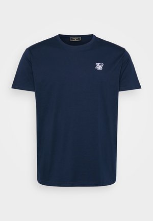 Tamnoplava pamučna majica s okruglim izrezom i kratkim rukavima. Sadrži bijeli izvezeni logo na lijevoj strani prsa. Glatka tekstura.