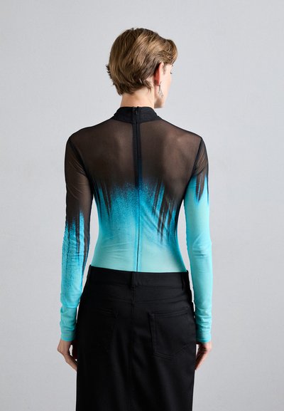 Body a maniche lunghe con un design sfumato che va dal nero all'acqua, dotato di pannelli trasparenti e zip sul retro. Indossato con una gonna nera.