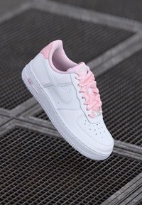 Sneaker in pelle bianca con dettagli rosa, lacci rotondi e punta forata. Sole in gomma con battistrada testurizzato e logo laterale marchiato.