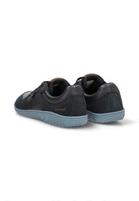 Zapatos de cuero negro con una superficie texturizada y una suela de goma azul, presentando un diseño de perfil bajo y una sutil marca en el talón.