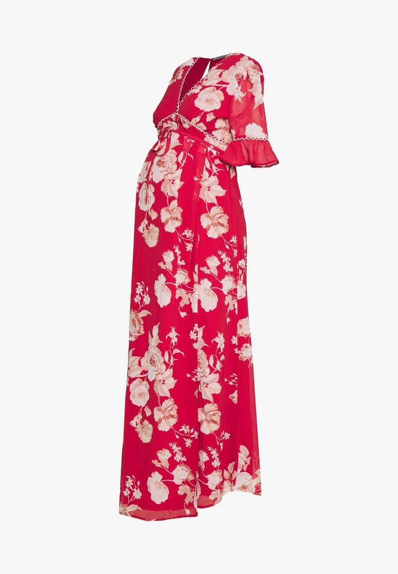 Punainen kukallinen maksimekko, jossa on lyhyet, röyhelöiset hihat, vyötärö on istuva ja vaate on valmistettu virtaavasta kankaasta, johon on kuvioitu suuria vaaleanpunaisia kukkia.