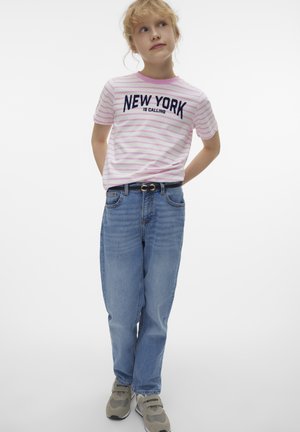Randig rosa och vit t-shirt med texten "NEW YORK IS CALLING", blå jeans och grå sneakers med svarta accenter, stående pose.
