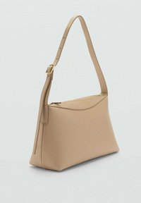 Bolso de hombro beige con forma estructurada, textura suave y parte superior curva. Cuenta con una correa delgada ajustable y un cierre de cremallera dorada.