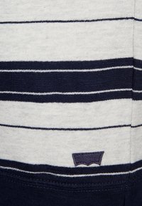 Tessuto a righe in grigio e blu navy, con strisce orizzontali e un piccolo logo ricamato. Texture morbida, design casual, adatto per un uso quotidiano.