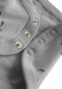 Body en tissu gris avec pressions, arborant de petits motifs floraux en bleu et orange. Texture douce avec des bords côtelés et des fermetures à pression métalliques.