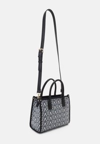 Sac structuré avec des accents en cuir noir, présentant un motif zigzag bleu et blanc. Il comprend deux poignées courtes et une longue bandoulière réglable.