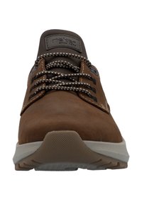 Chaussure en cuir marron avec un bout rond, tige grise contrastante et semelle en caoutchouc texturée. Présente des lacets épais et à motifs ainsi qu'une étiquette de logo.