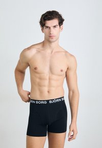 Boxers noirs en tissu doux, dotés d'une bande logo blanche autour de la taille. Le design est ajusté et d'une texture lisse.