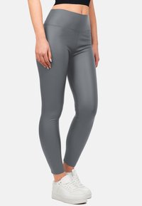 Leggings grigi alti in vita realizzati in un materiale liscio e elastico con una silhouette aderente, abbinati a sneakers bianche per un look casual.