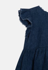 Ciemnoniebieska sukienka z lnu z falbanastymi rękawami i detalem w talii w białym tle.