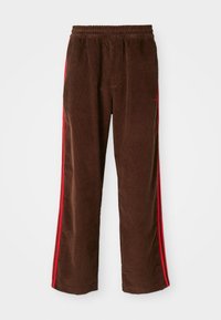 Brown corduroy pants with an elastic waistband, featuring red side stripes and straight legs. Textured fabric with subtle ribbing details.