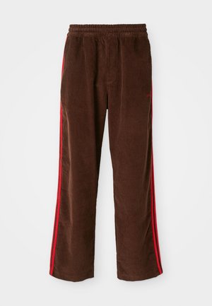 Pantaloni in velluto a coste marroni con una fascia elastica in vita, con strisce laterali rosse e gamba dritta. Tessuto testurizzato con sottili dettagli rigati.