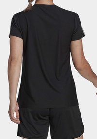 Camiseta deportiva negra con un patrón texturizado, mangas cortas y un corte relajado, combinada con pantalones cortos negros a juego.