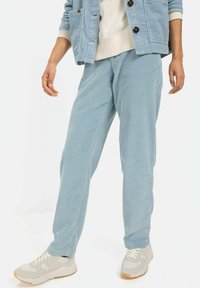 Lysblå corduroybukser med en afslappet pasform, der har lodrette striber, sidelommer og en glat tekstur. Båret med beige sneakers.