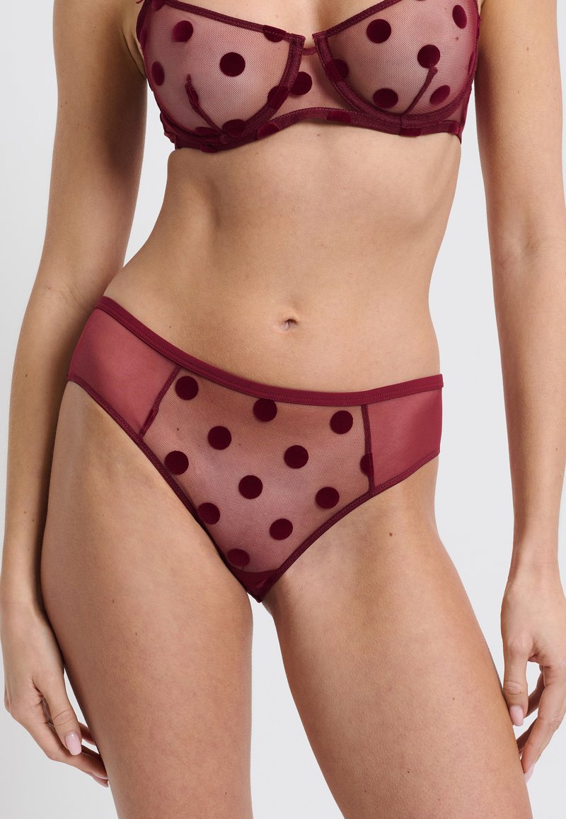 Burgundowe przezroczyste komplety bielizny z kropkami, bez podszewki biustonosz z fiszbinami oraz pasujące wysokie majtki o gładkim wykończeniu.
