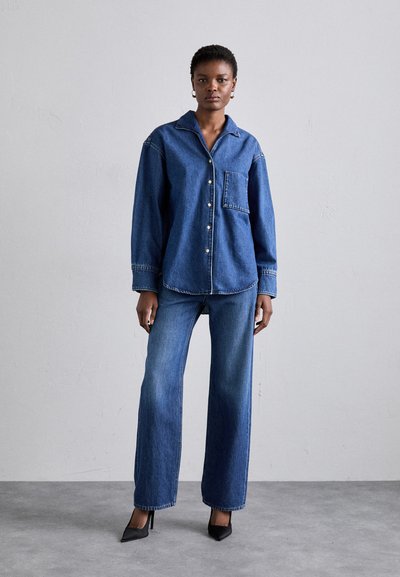 Denim shirt with a collar, button closure, and chest pocket, paired with wide-leg denim jeans. Both pieces are in a medium blue wash.