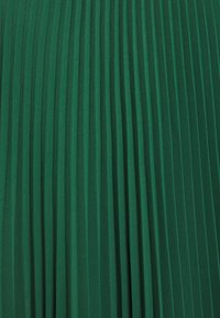 Tissu plissé vert avec des rayures verticales, présentant une surface texturée et un design uniforme sur toute la surface. Matériau doux et fluide.