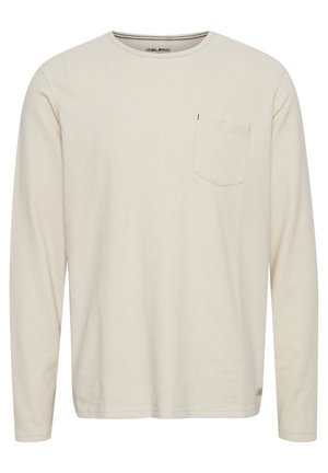 Pikkade varrukatega kreemjasärgid, mis on valmistatud pehmest puuvillast, ümar kaelus ja vasakul rinnal tasku, peened tekstuurid ja õmbluse detailid.