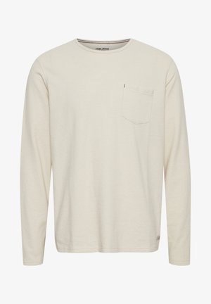 Pikkade varrukatega kreemjasärgid, mis on valmistatud pehmest puuvillast, ümar kaelus ja vasakul rinnal tasku, peened tekstuurid ja õmbluse detailid.