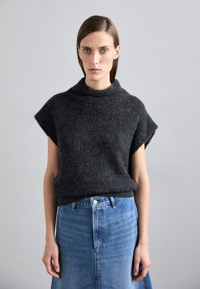 Pull en maille gris foncé avec un col roulé haut et des manches courtes, associé à une jupe en denim bleu clair avec une taille à boutons.