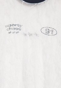 Tissu en dentelle blanche avec texte imprimé noir "sporty chaos" et numéro "97" à l'intérieur d'un ovale, avec des étoiles entre les textes.