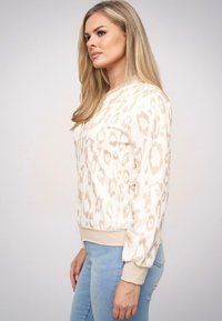 Beżowy i kremowy sweatshirt w leopardzi wzór, z prążkowanymi mankietami i dołem. Długie rękawy i okrągły dekolt. Teksturowany materiał.