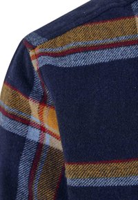 Marinblå flanellstoff med et rutet mønster i gult, rødt og lyseblått. Teksturen ser myk og litt bustete ut.