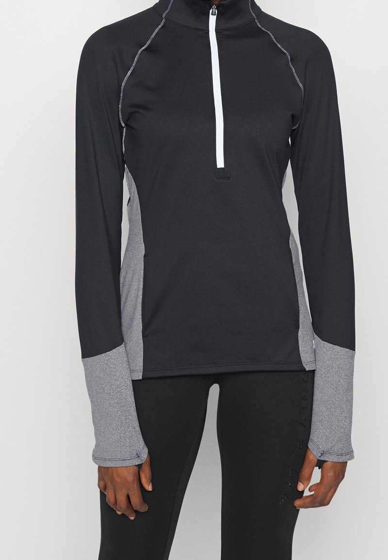 Black athletic top with a quarter zip, grey side panels, and long sleeves featuring thumbholes, made from a smooth, stretchy fabric.