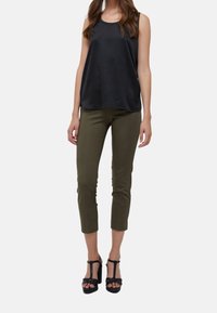 Czarny bezrękawnik w połączeniu z oliwkowymi spodniami 3/4 oraz czarnymi sandałami na wysokim obcasie, prezentujący gładki materiał i prosty krój.