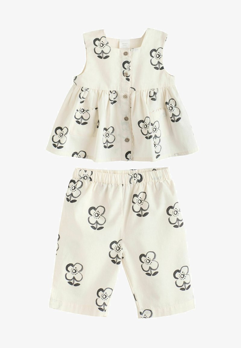 Ensemble haut sans manches et short couleur crème avec imprimé fleurs noir et blanc, fermeture par boutons sur le devant du haut, et taille élastique au short.