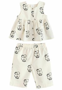 Zweiteiliges Kinderoutfit bestehend aus einem ärmellosen, cremefarbenen Oberteil mit schwarzen Blumenmustern und passenden Shorts, die ebenfalls mit Blumen verziert sind.