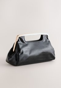 Melnas mākslīgās ādas soma ar krokodila rakstu, ar metālisku zelta rokturi un strukturētu formu, izstrādāta ar plašu iekšpusi.