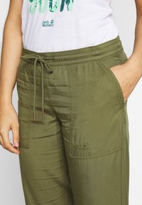 Lättviktiga olivgröna byxor med elastisk midja, justerbar dragsko och sidofickor. Försedd med Jack Wolfskin-logga på fickan.