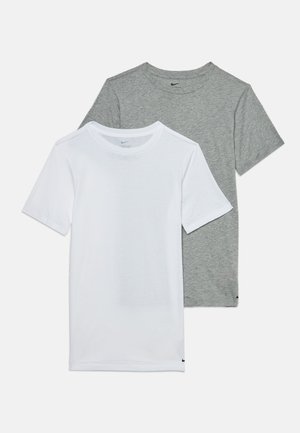 Δύο μονόχρωμα κοντομάνικα μπλουζάκια Nike, ένα λευκό και ένα γκρι, τοποθετημένα επίπεδα με μερική επικάλυψη σε λευκό φόντο.