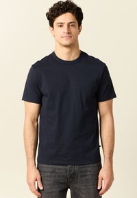 T-shirt a maniche corte blu navy in cotone, scollo rotondo, design semplice, colore uniforme, vestibilità attillata, senza motivi o decorazioni visibili.
