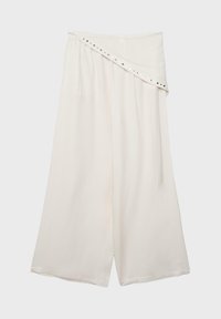 Pantalon blanc à jambes larges avec une ceinture asymétriquement repliée ornée de petits clous métalliques le long du bord.