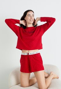 Röd bomullspyjamasset bestående av en kortärmad topp med prickar och shorts med resårmidja och logodetalj.
