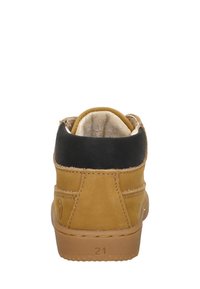 Tan suède enkellaars met een zwarte leren manchet, een gestructureerd oppervlak en een rubberen zool. Maat 21 gemarkeerd aan de buitenkant.
