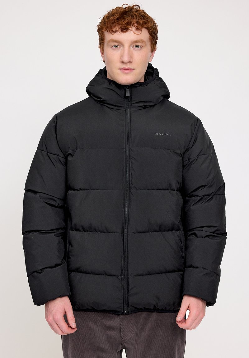 Schwarze Puffjacke mit Kapuze, ausgestattet mit einem gesteppten Design, einem Frontreißverschluss und einem Logodetail auf der Brust. Glatte, matte Oberfläche.