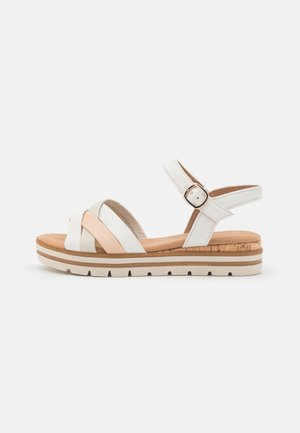 Witte en beige damessandaal met verstelbare enkelriem, gevoerde kurken voetbed en geribbelde rubberen zool, geschikt voor casual gebruik.