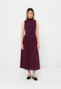 Mauve sleeveless dress with a fitted bodice and flowing ankle-length skirt, made from lightweight fabric. Black flats complete the look.