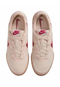 Sneakers Nike rosa chiaro con loghi swoosh rossi, lacci allacciati e suole color gomma mostrati dall'alto affiancati.