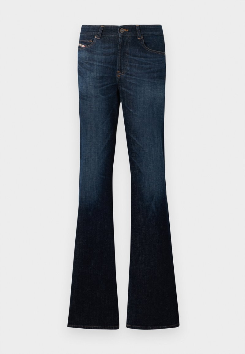 Vaqueros de mezclilla azul oscuro con un leve desgaste y piernas anchas acampanadas sobre un fondo blanco liso.