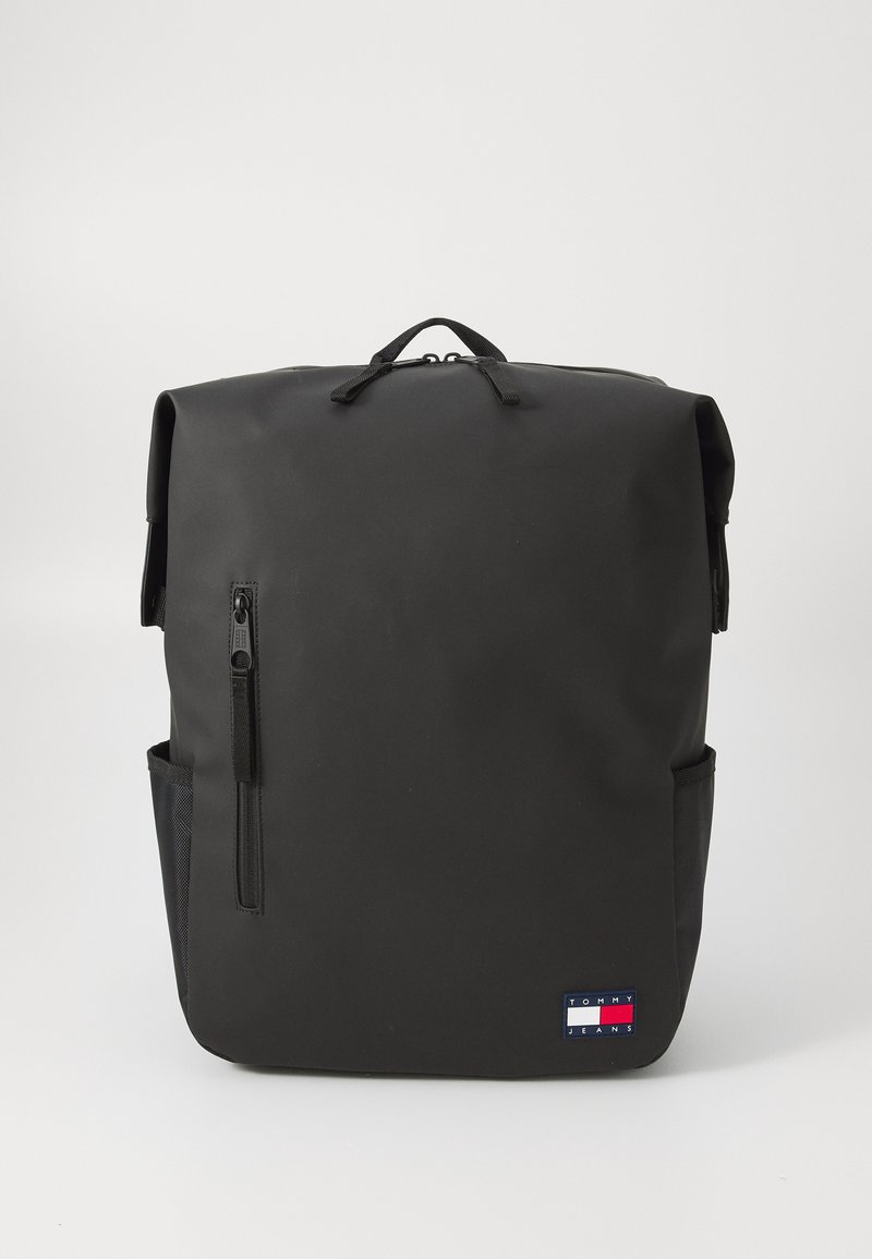 Svart ryggsekk med rull-topp design, glidelåslomme foran, sidelomme i mesh og et lite logo-patch nederst. Vanntett materiale.